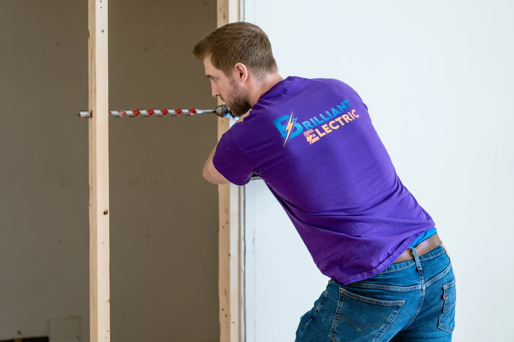 Paul drilling a wall during electrical installation work at a residential property