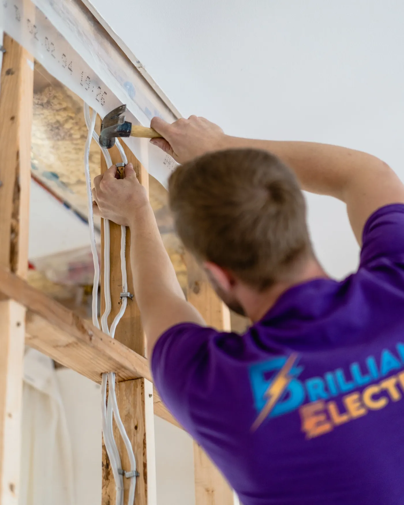 Paul installing electrical wiring through wall framing on a renovation site