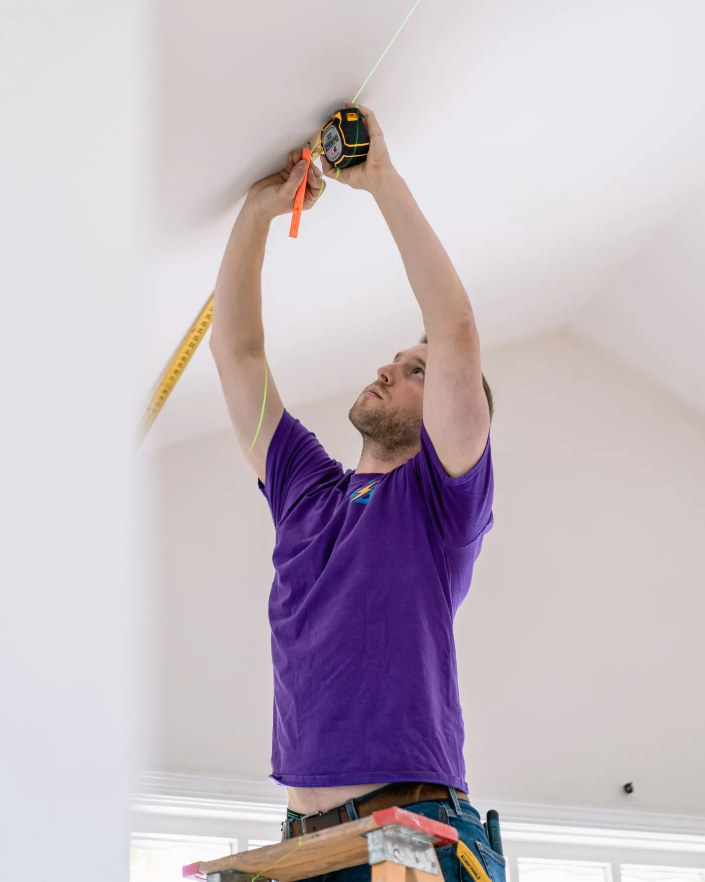 Paul measuring a ceiling for a lighting or electrical fixture installation