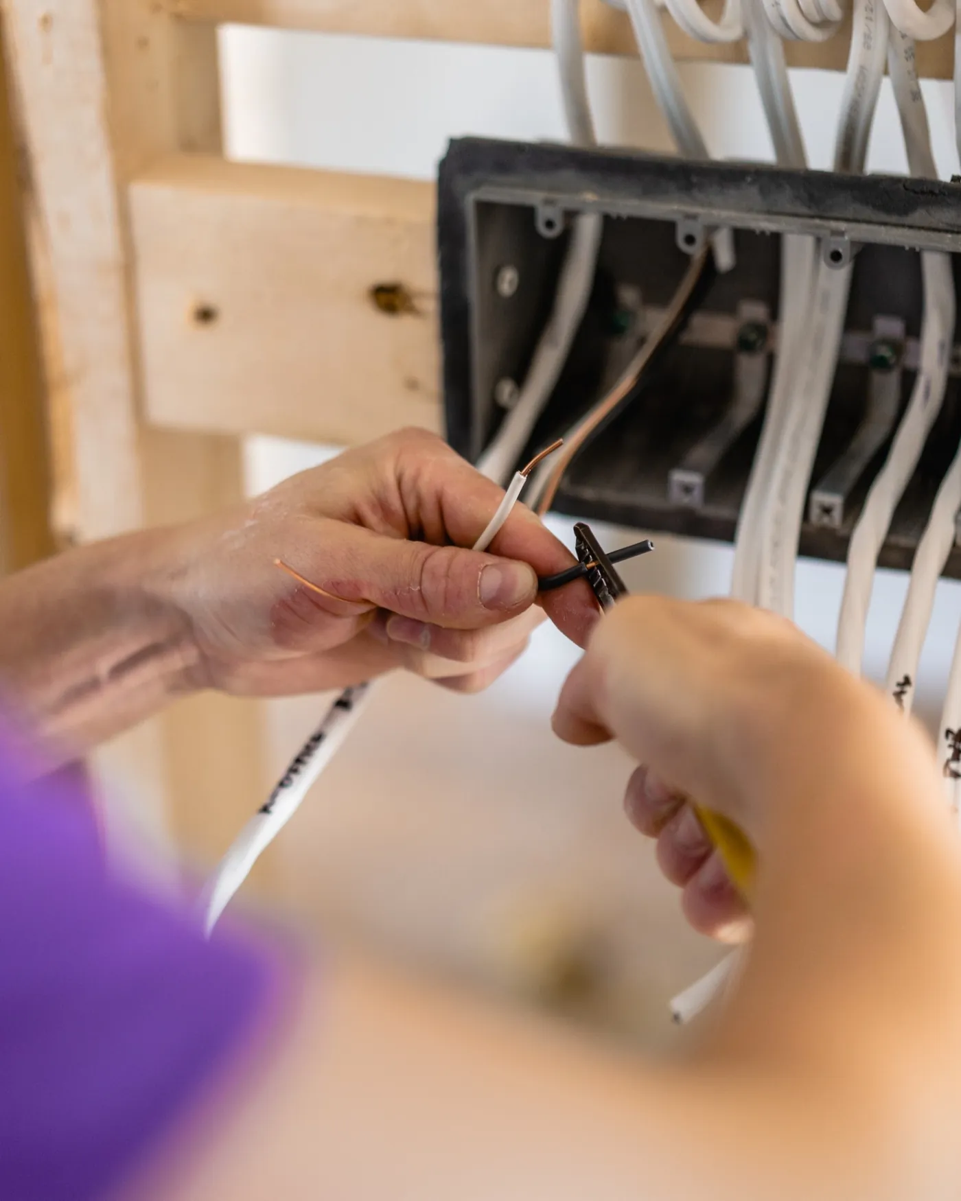 Close-up of Paul preparing electrical conductors at a wall box